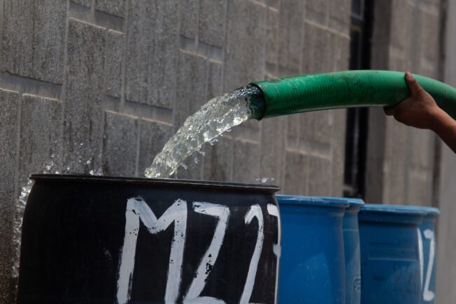 Un trabajador de una pipa de agua abasteció los tambos del vital líquido en la colonia Rubén Jaramillo