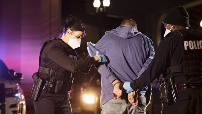 Criminal suspect being handcuffed by police at night